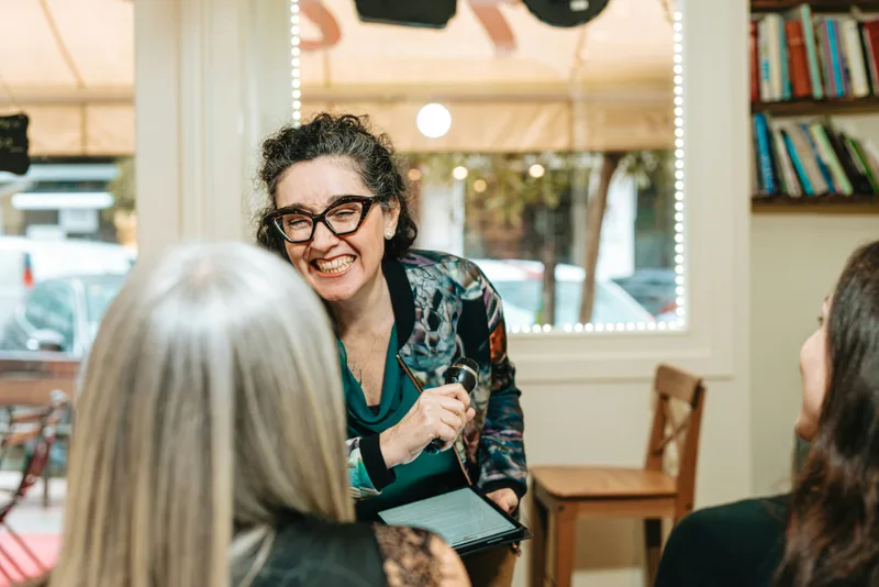 Smiling business owner interviewing customers in her café